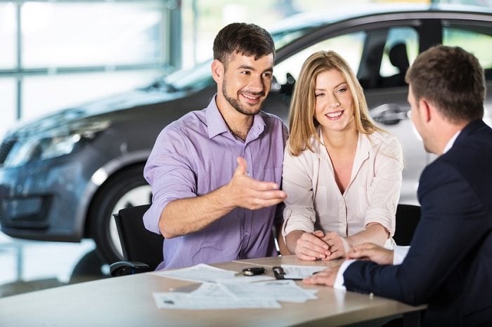 Couple asking questions of a salesman at an auto dealership