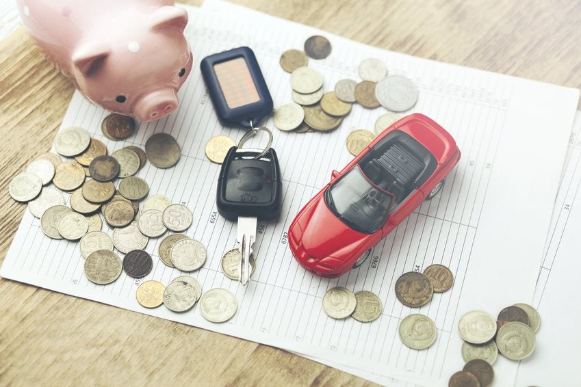 Toy car with piggy bank and money over new vehicle leasing forms